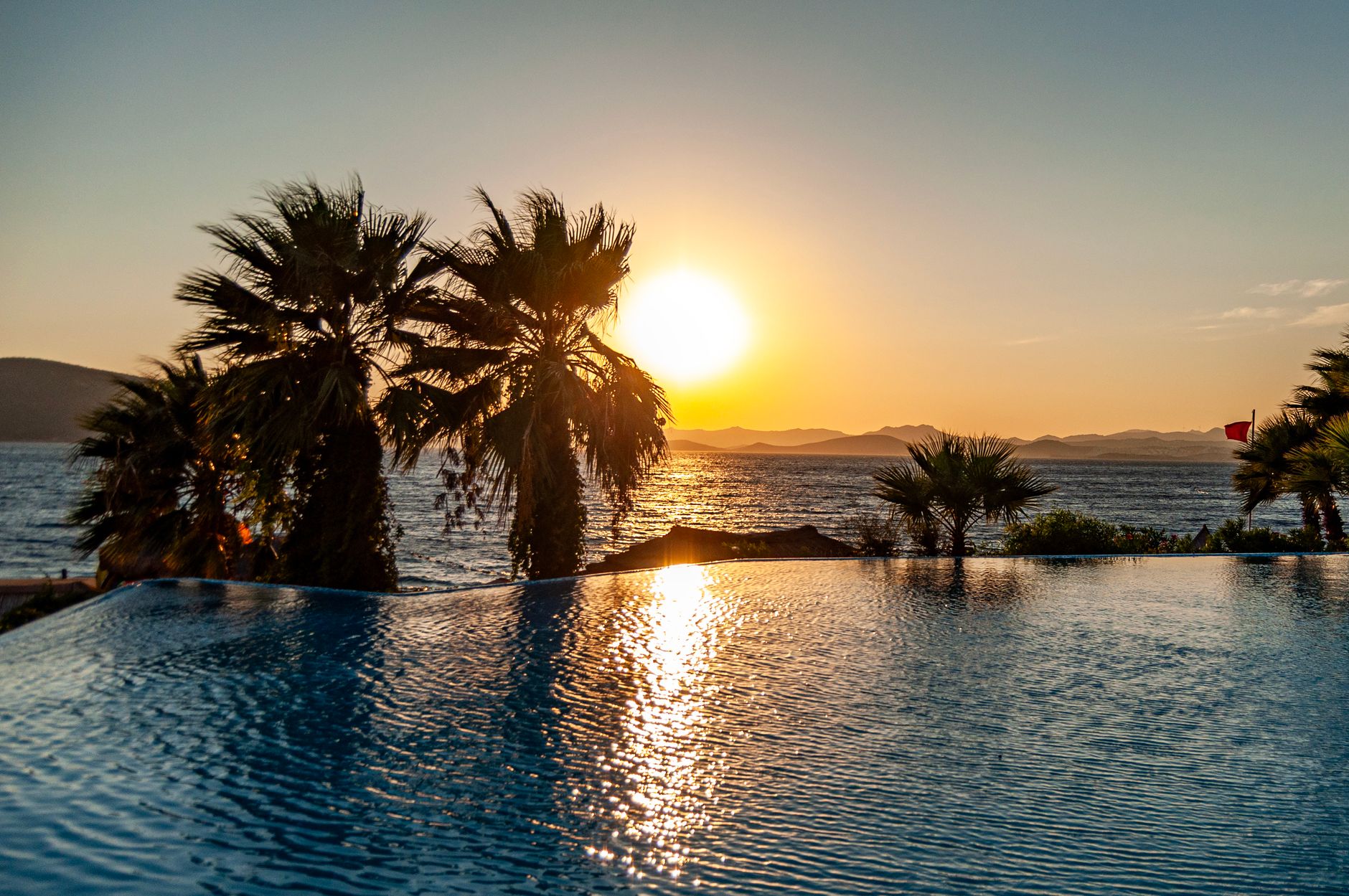 Stunning sunset view over an infinity pool with palm trees