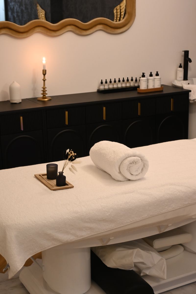 Elegant spa room with rolled towel, candle, and essential oils on massage table